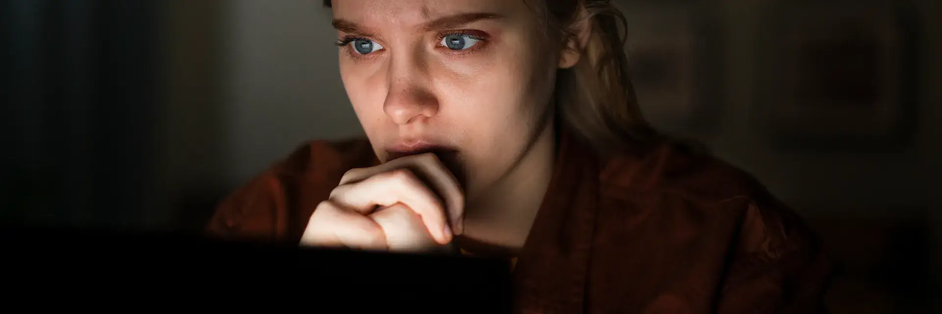 Concerned woman using a laptop in a dark room