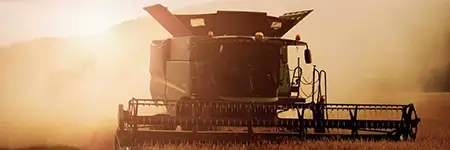 Combine harvester plowing fields at dusk