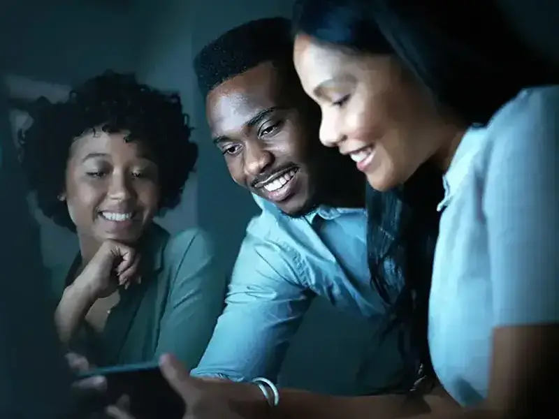 Three people smiling while looking at phone