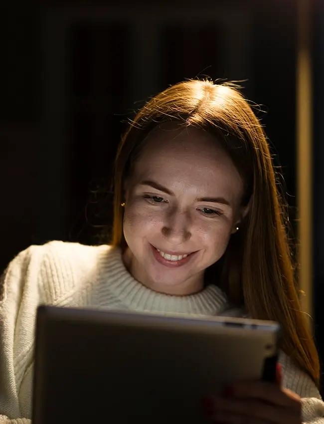 Woman smiling while looking at tablet